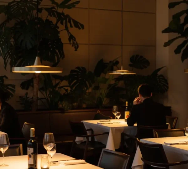 Salle de restaurant élégante avec éclairage tamisé et séparations végétales créant une ambiance intimiste